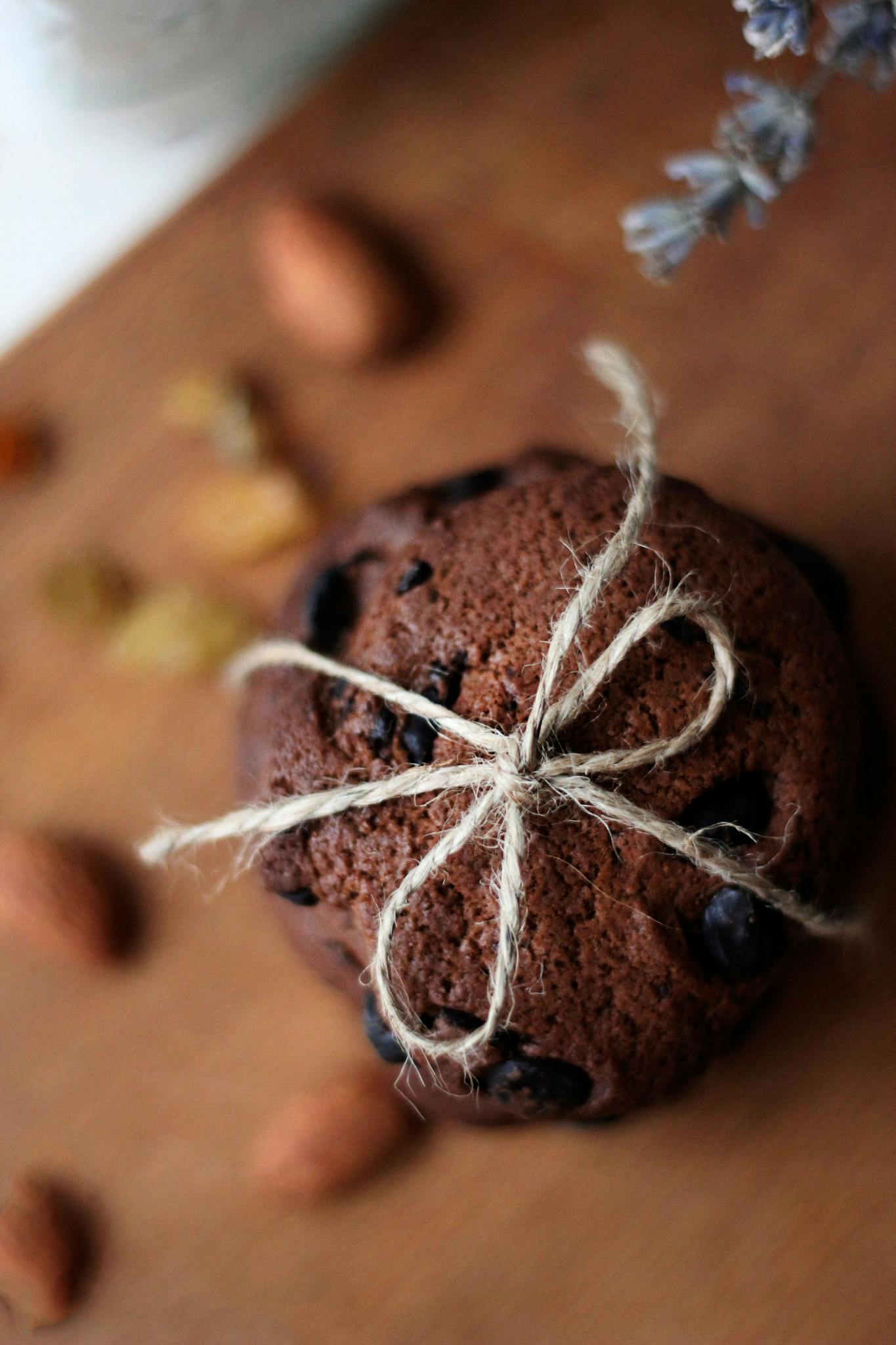 Close-up of a chocolate cookie wrapped with twine, artfully displayed on a wooden board.