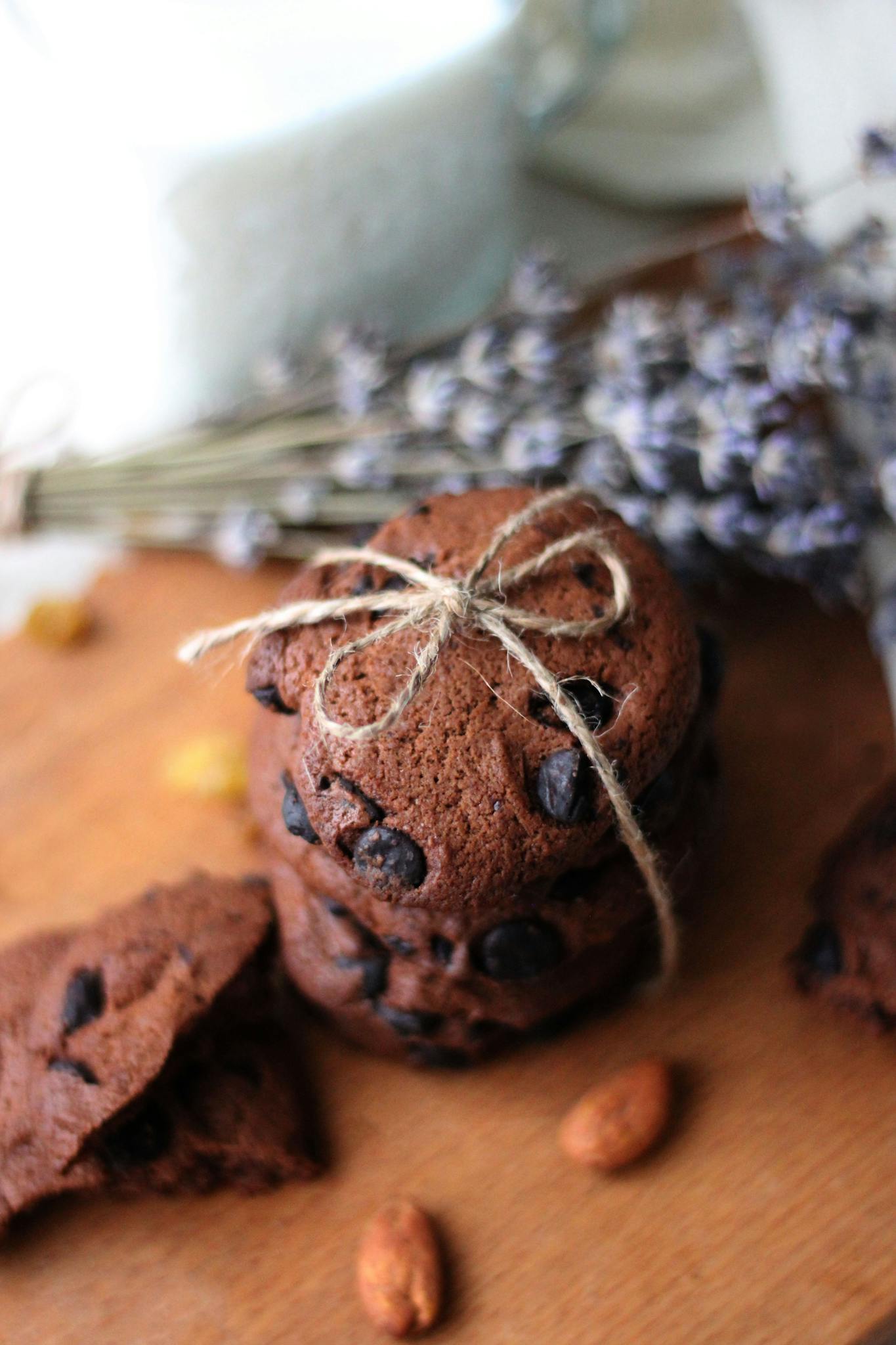 Close-up of chocolate chip cookies stacked with rustic twine, surrounded by almonds and lavender.