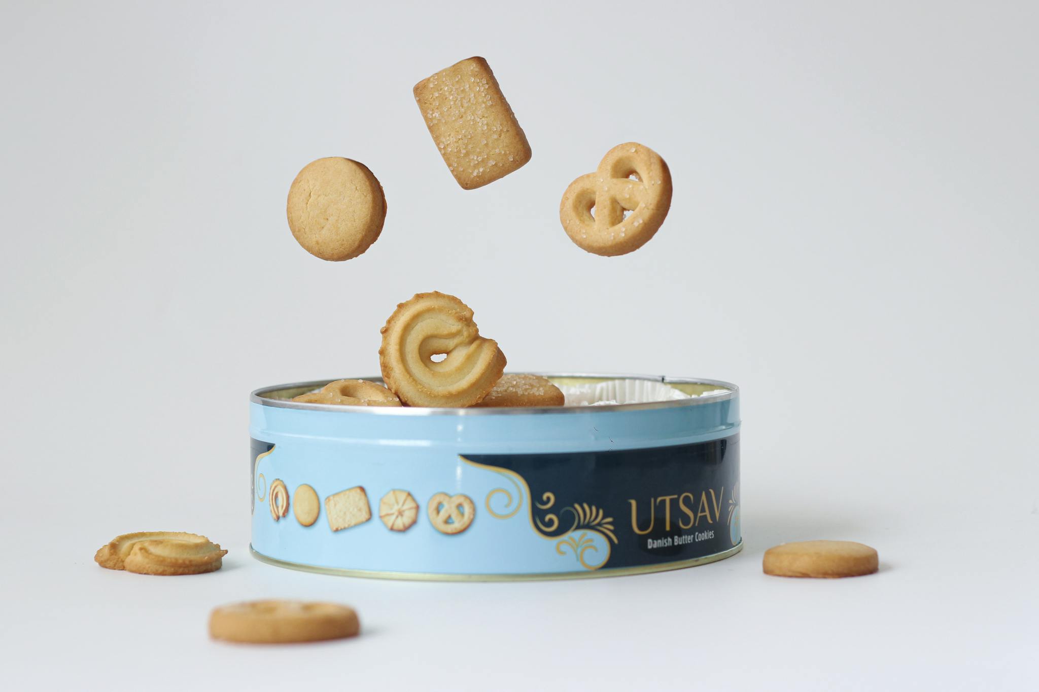 Floating Danish butter cookies above a decorative tin. Perfect for food-themed visuals.