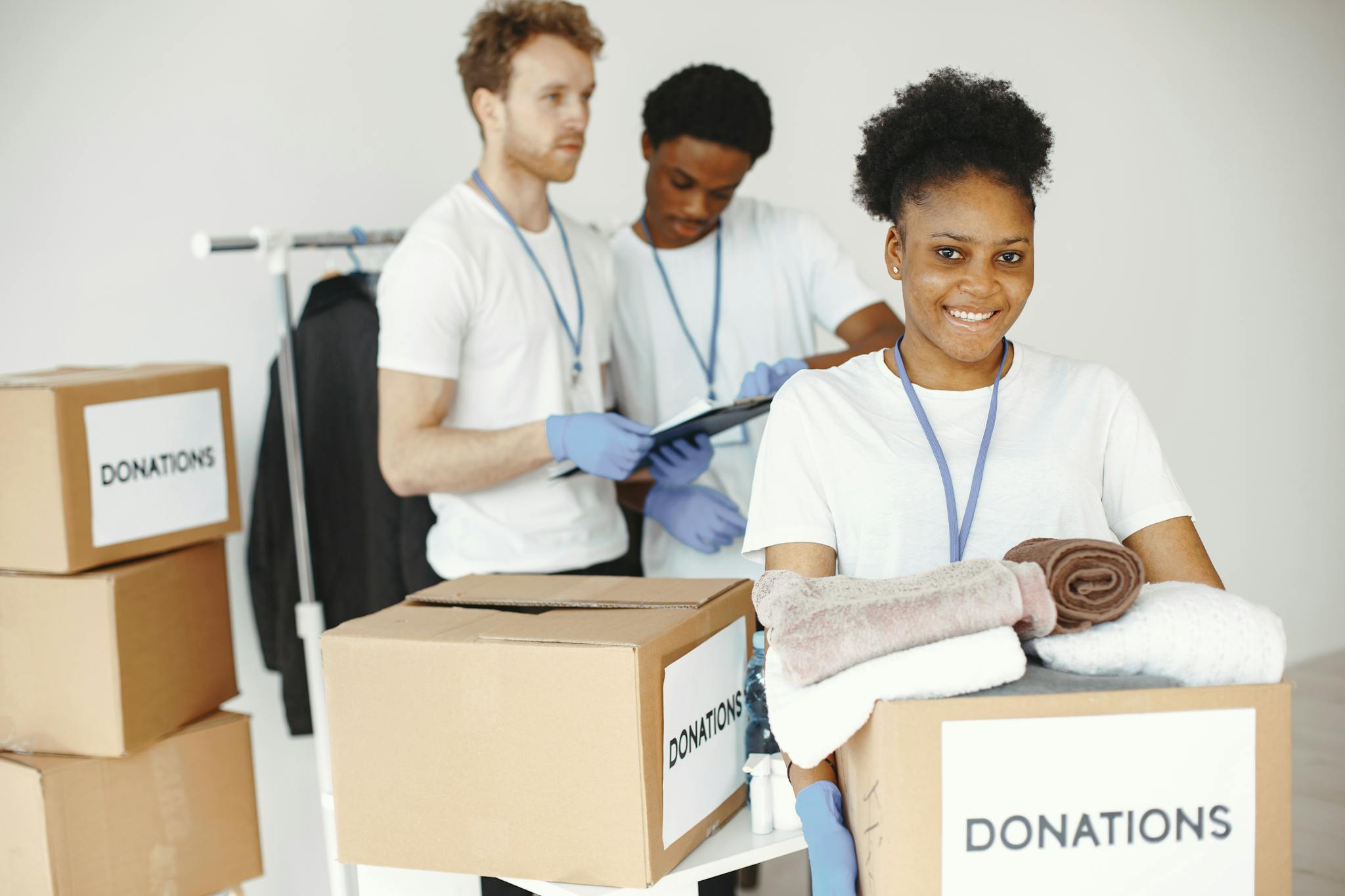 Group of volunteers smiling while sorting donation boxes indoors for a charity organization.