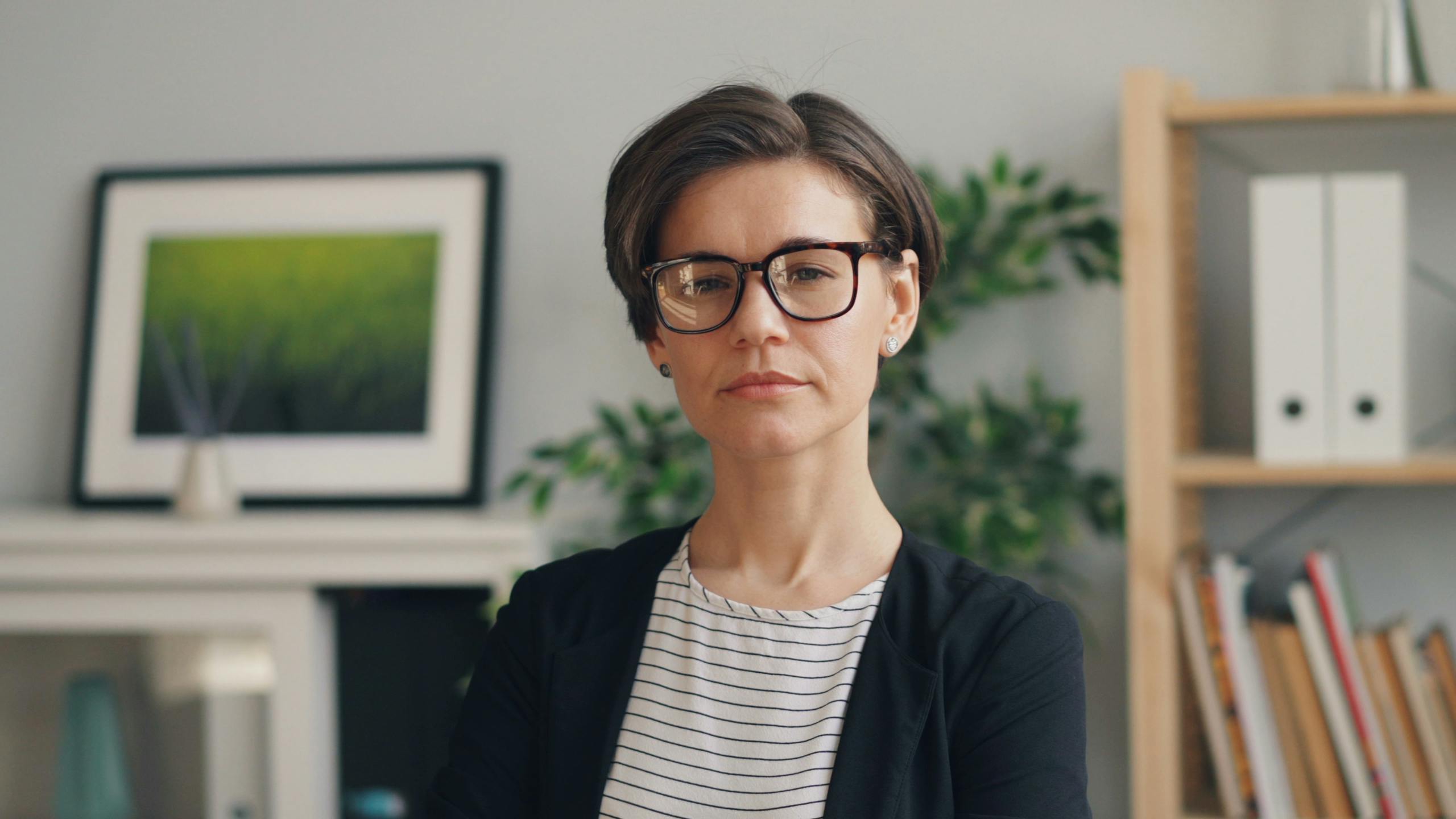 Portrait of a confident businesswoman in a modern office setting wearing eyewear.