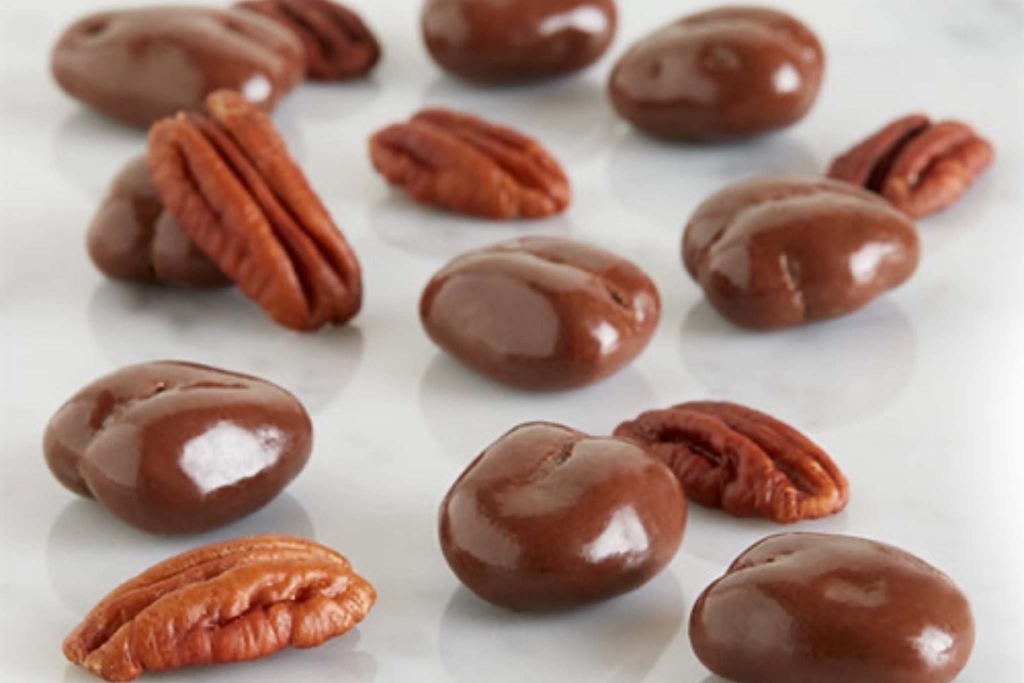A close-up of roasted California almonds thickly coated in smooth milk chocolate, displayed in a signature World's Finest Chocolate tin.