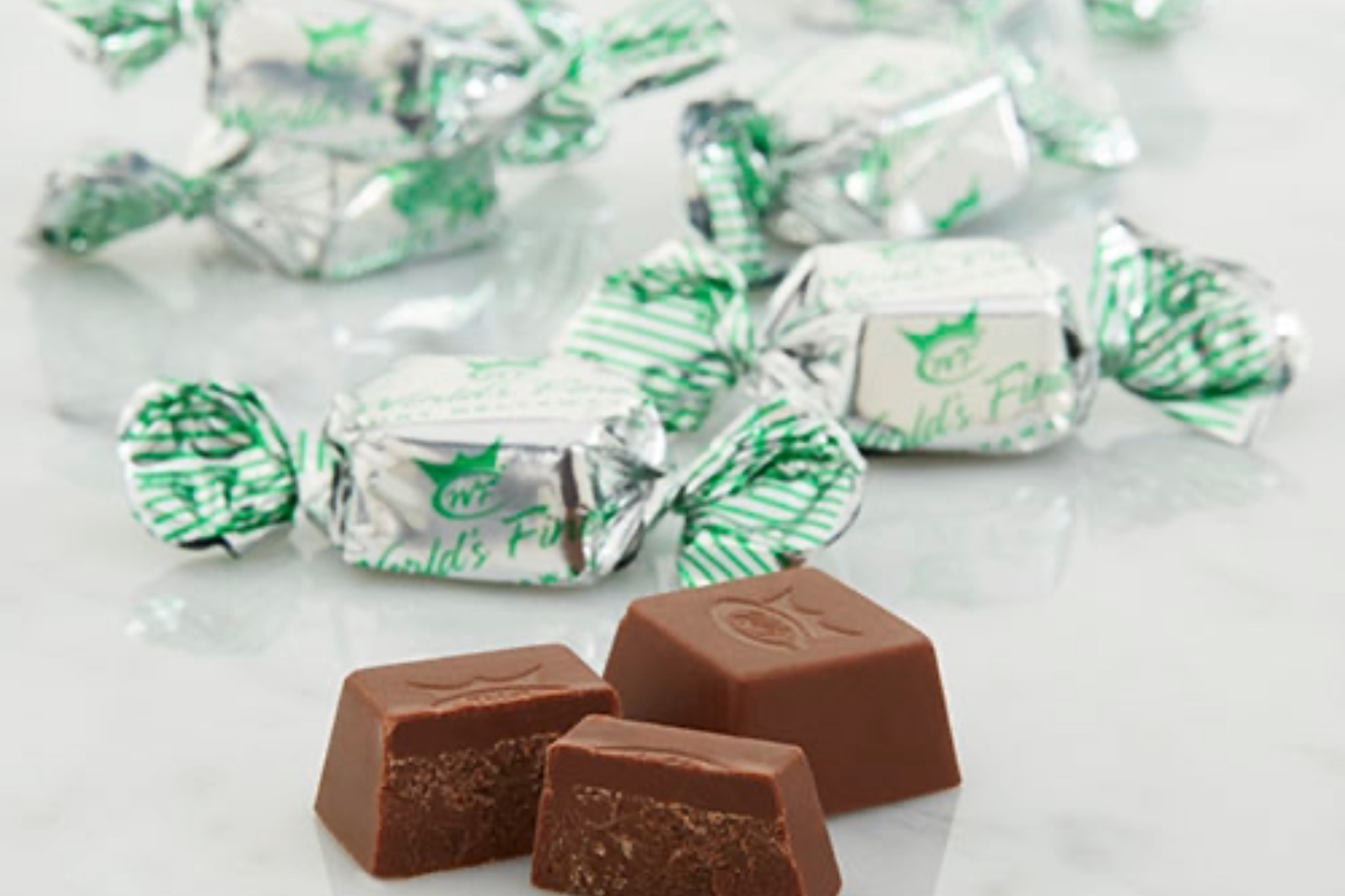 Square milk chocolate candies with a soft green mint center, shown in a World's Finest Chocolate $2 fundraising box.